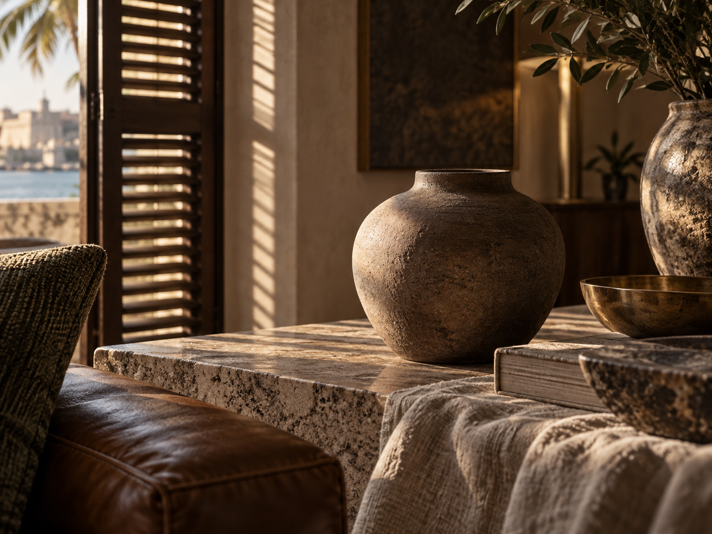 A close material study of leather, linen, stone, and a weathered ceramic vessel in warm louvered light.